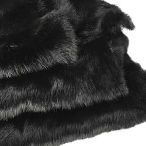 May include: A black faux fur throw blanket. The blanket is folded in thirds and the texture of the fur is visible.