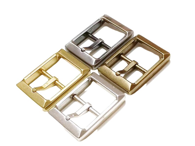 Pu&ograve; includere: Quattro fibbie per cintura in metallo in diverse finiture: argento, oro, ottone e nichel. Le fibbie sono tutte della stessa dimensione e forma, con una cornice rettangolare e una barra centrale con un piccolo anello.
