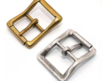 May include: Two metal belt buckles, one gold and one silver. Both buckles are rectangular with rounded corners and have a simple design.