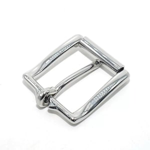 May include: A shiny, silver-colored belt buckle with a rectangular shape. The buckle has a classic design with a single bar and a rounded, curved frame. The metal has a polished, reflective surface.
