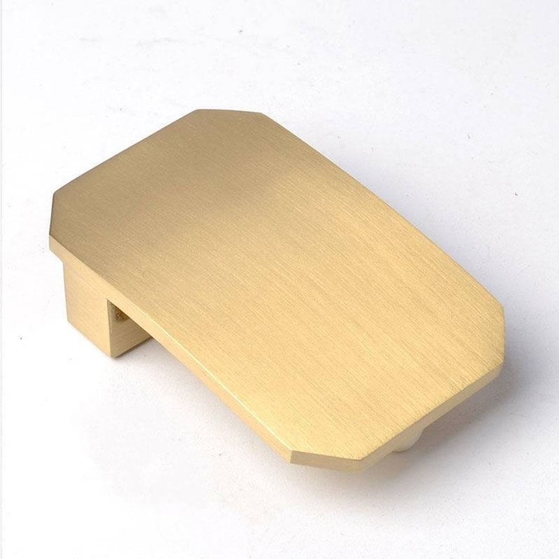K&ouml;nnte beinhalten: Eine rechteckige, leicht abgerundete G&uuml;rtelschnalle aus geb&uuml;rstetem Goldmetall.
