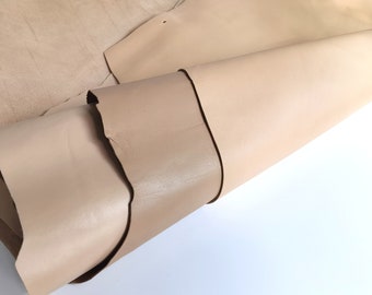 May include: A close-up of a folded piece of light brown leather. The leather has a smooth, slightly shiny surface.