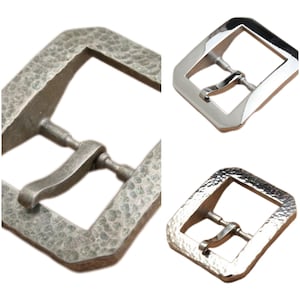 May include: Three metal belt buckles with a hammered finish. The buckles are silver, chrome, and a darker silver color. The buckles are all the same size and shape, with a rectangular frame and a single prong.