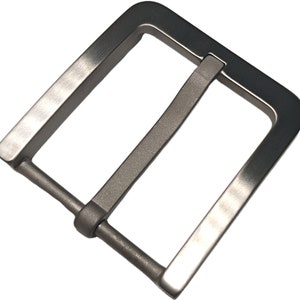 Puede incluir: Una hebilla de cinturón de metal plateado con forma rectangular y un acabado liso y cepillado.