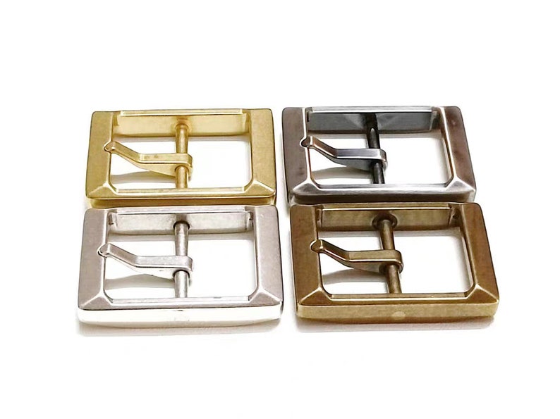 Pu&ograve; includere: Quattro fibbie per cintura in metallo in diverse finiture: oro, argento, nero e ottone. Ogni fibbia &egrave; rettangolare con una superficie liscia e un solo perno.