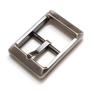 Pu&ograve; includere: Una fibbia in metallo argentato di forma rettangolare con finitura liscia. La fibbia ha un solo perno e un design semplice.