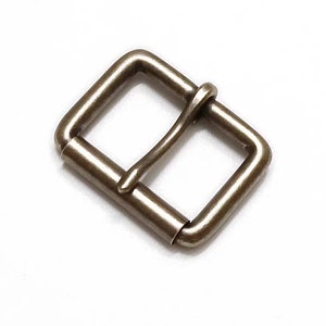 May include: A silver-toned metal buckle with a rectangular shape and a smooth finish.
