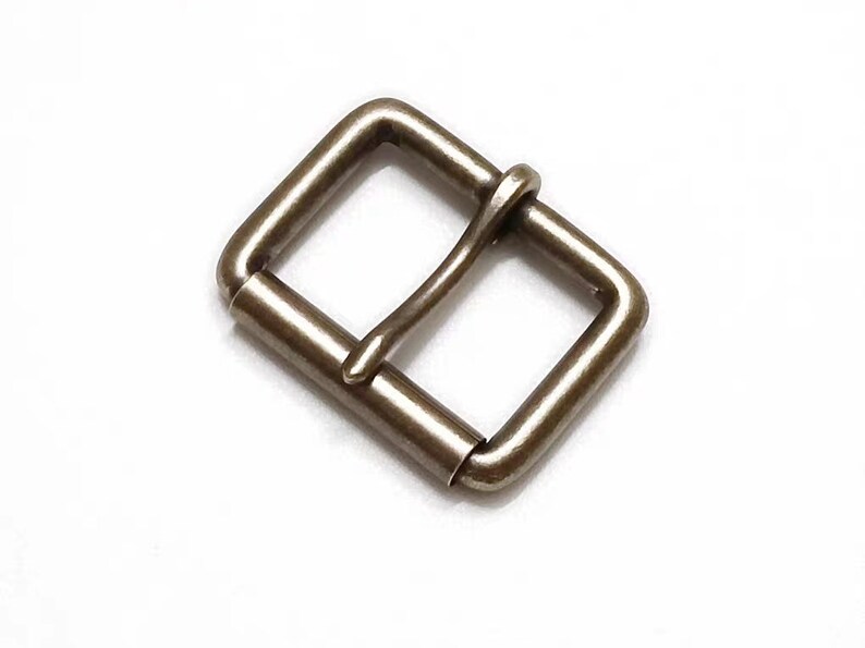 May include: A silver-toned metal buckle with a rectangular shape and a smooth finish.