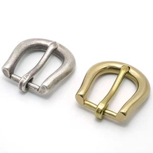 May include: Two metal belt buckles, one silver and one gold. Both buckles are in the shape of a horseshoe with a rounded top and a flat bottom.