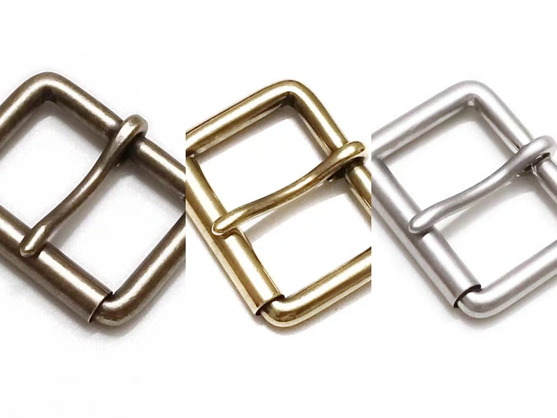 May include: Three metal belt buckles in different finishes: silver, brass, and antique brass. Each buckle is a simple, rectangular design with a smooth, polished finish.