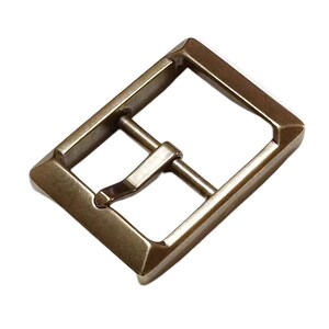 Pu&ograve; includere: Una fibbia in metallo dorato di forma rettangolare con finitura liscia. La fibbia ha un solo gancio e un design semplice.