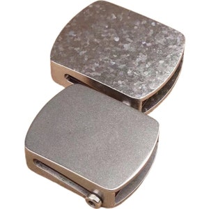 May include: Two silver metal belt buckle clasps. The top clasp has a textured surface and the bottom clasp has a smooth surface.