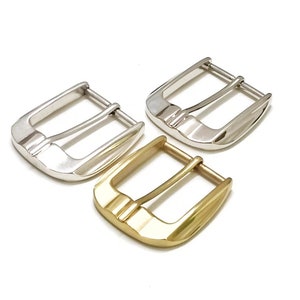 May include: Three metal belt buckles in different finishes: silver, gold, and nickel. The buckles are all the same size and shape, with a rectangular frame and a double prong.