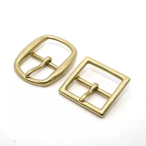 Peut inclure: Deux boucles de ceinture en métal doré. Une boucle est rectangulaire et l'autre est ovale.
