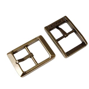 Pu&ograve; includere: Due fibbie per cintura in metallo color oro antico. La fibbia a sinistra &egrave; semplice, mentre la fibbia a destra ha le parole "SOLID BRASS" incise.