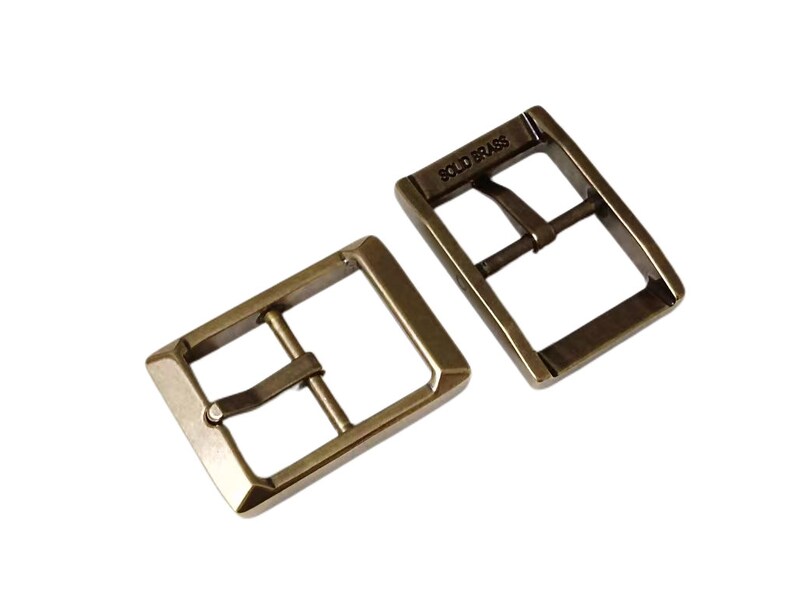 Pu&ograve; includere: Due fibbie per cintura in metallo color oro antico. La fibbia a sinistra &egrave; semplice, mentre la fibbia a destra ha le parole "SOLID BRASS" incise.
