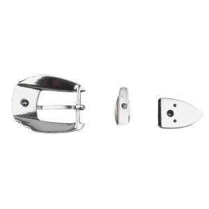 Puede incluir: Una hebilla de cintur&oacute;n de metal plateado con un dise&ntilde;o liso y curvo. La hebilla tiene una sola punta y un peque&ntilde;o agujero redondo en la parte superior. La hebilla se muestra con dos piezas de metal separadas, una rectangular y otra con forma de peque&ntilde;o tri&aacute;ngulo puntiagudo.