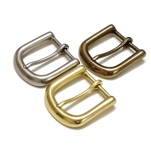 Può includere: Tre fibbie per cintura in metallo in diverse finiture: argento, ottone e oro. Ogni fibbia ha un design semplice e classico.