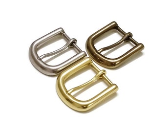 Könnte beinhalten: Drei Metall-Gürtelschnallen in verschiedenen Ausführungen: Silber, Messing und Gold. Jede Schnalle hat ein schlichtes, klassisches Design.