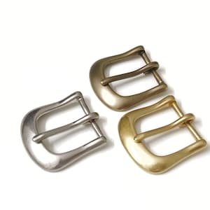 May include: Two metal belt buckles, one silver and one gold. Both buckles have a double prong design.
