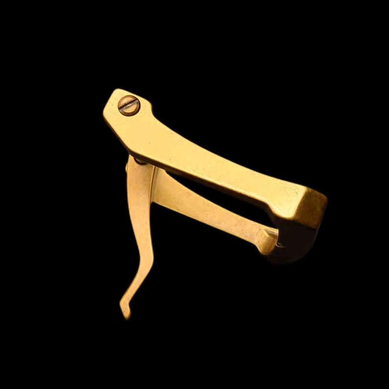 May include: A gold-colored metal tool with a lever and a screw. The tool is designed to open and close watch bands.