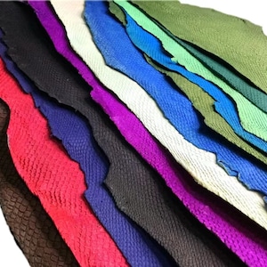 May include: A stack of different colored leather hides with a textured pattern. The hides are arranged in a diagonal pattern, with the darkest color at the bottom and the lightest color at the top.