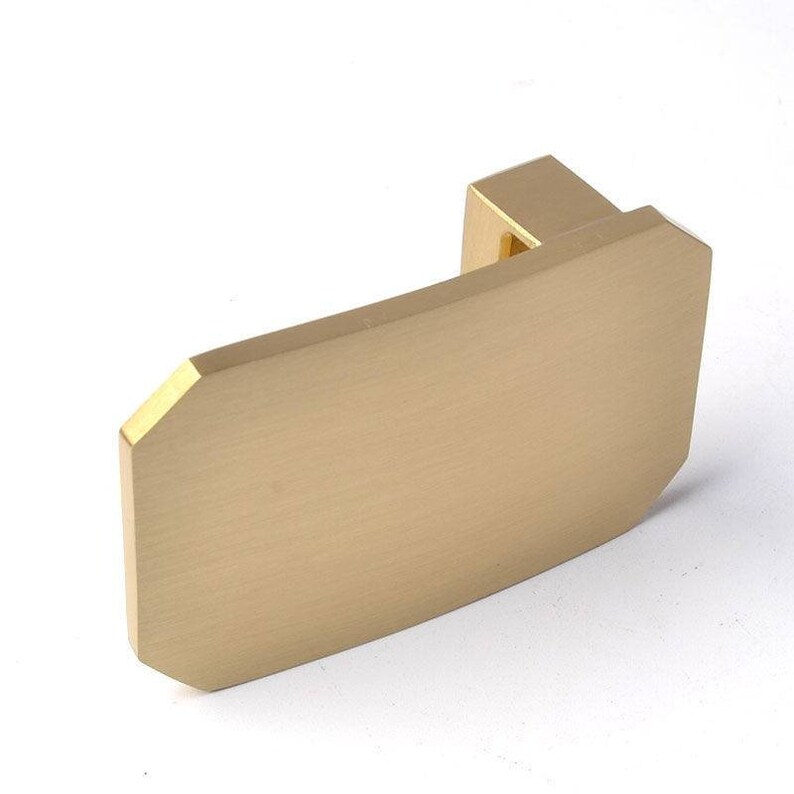 K&ouml;nnte beinhalten: Ein goldfarbener, rechteckiger Schrankgriff aus Metall mit leicht abgerundeten Kanten. Der Griff hat ein schlichtes, modernes Design.