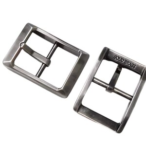 Pu&ograve; includere: Due fibbie per cintura in metallo argentato. La fibbia a destra ha le parole "SOLID BRASS" incise.