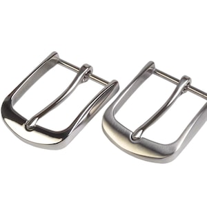 Puede incluir: Dos hebillas de cinturón plateadas. Las hebillas tienen forma rectangular con una barra curva para la correa del cinturón. Una hebilla tiene un acabado brillante, la otra un acabado mate. Son de metal y están diseñadas para cinturones.