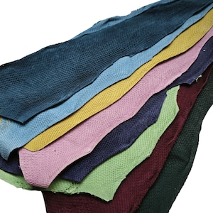 May include: A stack of different colored leather hides, each with a textured surface. The hides are arranged in a rainbow pattern, with the darkest color at the bottom and the lightest color at the top.