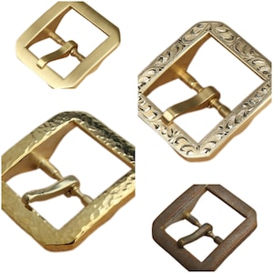 Può includere: Quattro stili diversi di fibbie per cinture in metallo. Le fibbie sono tutte dorate e hanno una forma quadrata. Le fibbie hanno design diversi, tra cui una finitura martellata, un design inciso e un design semplice.