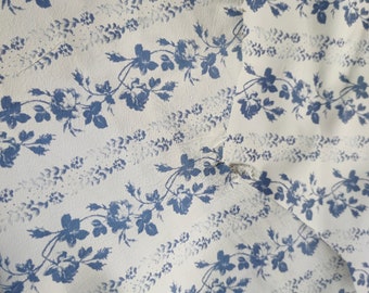 May include: White fabric with a blue floral pattern. The pattern features small blue flowers and leaves on a white background.