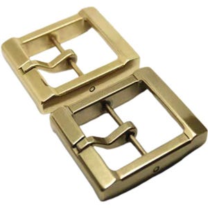 Könnte beinhalten: Zwei goldfarbene Metall-Gürtelschnallen. Jede Schnalle hat eine rechteckige Form mit einer glatten, polierten Oberfläche. Die Schnallen haben ein schlichtes, klassisches Design.