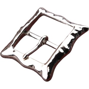 Op de afbeelding: Zilverkleurige metalen gesp met een getextureerde, onregelmatige vorm. De gesp heeft een rechthoekig frame met een gladde, afgeronde rand.