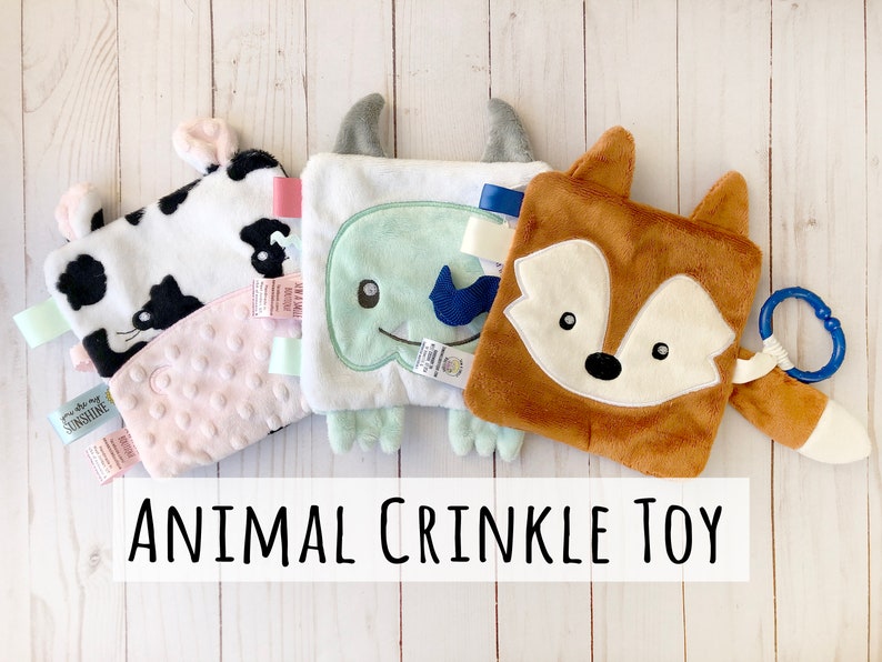 May include: Four plush animal crinkle toys for babies. The toys are a cow, a monster, a fox, and a pink textured toy. The toys are all soft and cuddly and have crinkly fabric.