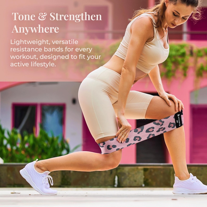 May include: A woman is using a pink resistance band with a black leopard print pattern during a workout. The text "Tone & Strengthen Anywhere" is visible in the background.