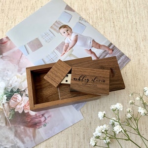 Può includere: Una scatola di legno con un coperchio scorrevole, che contiene un'unità USB con il testo "ashley olivia photography" inciso su di essa. La scatola è su un tavolo con uno sfondo bianco.