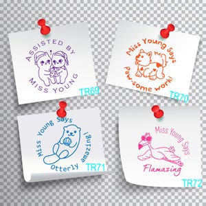 May include: Four white sticky notes with colorful illustrations and text. Each note has a red push pin in the top right corner. The text on the notes reads: "Assisted by Miss Young", "Miss Young Says Paw-some work!", "Miss Young Says Otterly amazing!" and "Miss Young Says Flamazing".