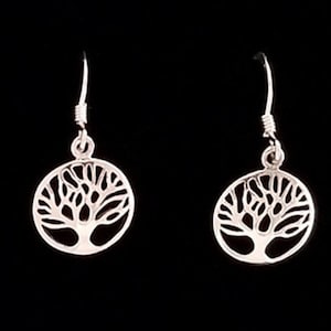 May include: A pair of silver dangle earrings featuring a tree of life design. The earrings are circular and have a delicate, intricate design.
