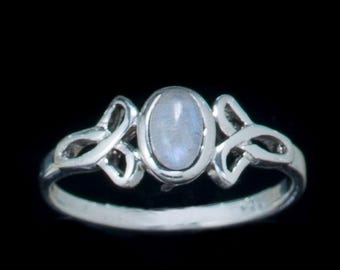 May include: A silver ring with a delicate Celtic knot design and a light blue oval moonstone.