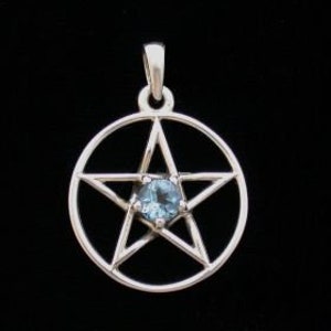 May include: A silver-colored pendant featuring a pentagram design. The pentagram is enclosed within a circle and has a small, round, light blue gemstone at its center. The pendant hangs from a small loop at the top.