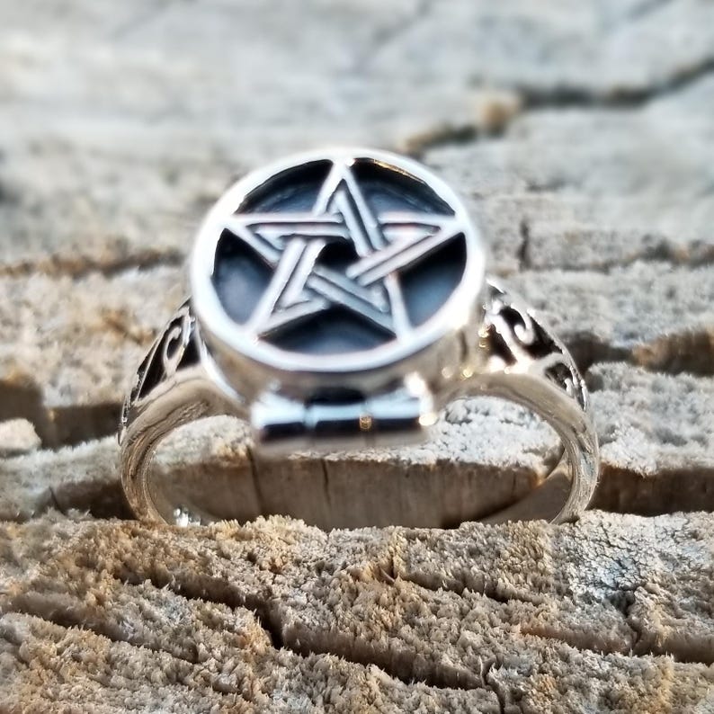 Op de afbeelding: Een zilveren ring met een pentagram-ontwerp aan de bovenkant. De ring is open en heeft een scharnierend deksel.