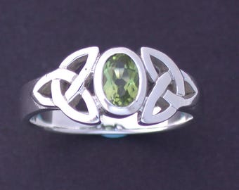 Può includere: Un anello d'argento con una pietra preziosa verde incastonata in un design a nodo celtico.