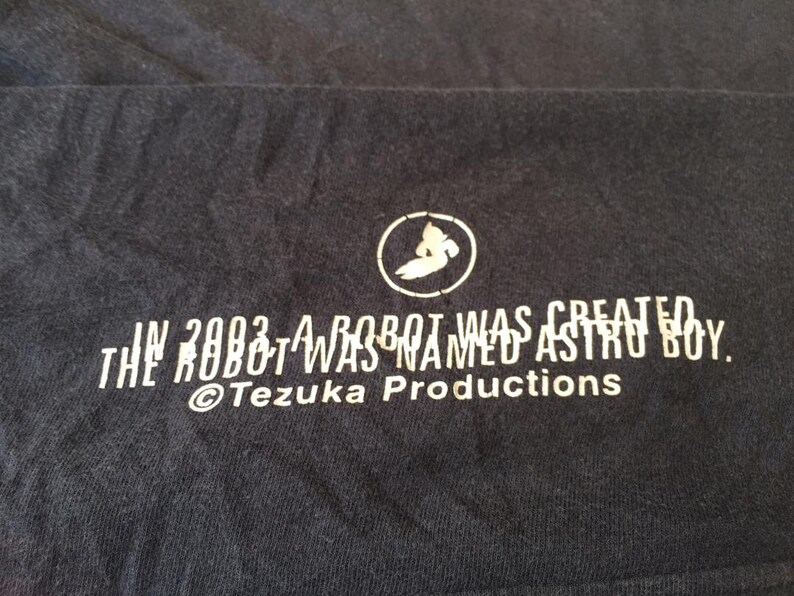 May include: A black t-shirt with white text that reads "In 2003 a robot was created. The robot was named Astro Boy. &copy;Tezuka Productions."