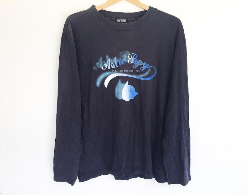 May include: A black long-sleeve shirt with a blue and white graphic print of Astro Boy and the text "Astro Boy &copy;Tezuka Productions".