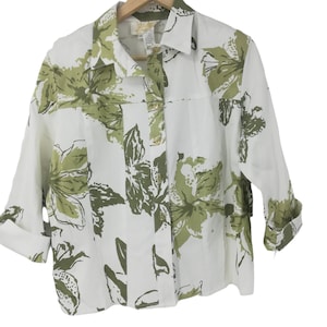Peut inclure: Chemise boutonnée blanche à imprimé floral vert. La chemise a un col et des manches longues.