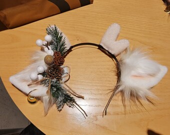 May include: White furry headband with a black headband, white fur ears, and a pine cone and berry embellishment.