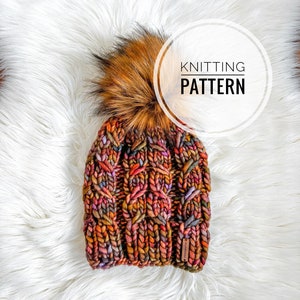 May include: A colourful knitted beanie with a large brown and black faux fur pom pom. The beanie has a cable knit pattern and is made with a chunky yarn. The text "KNITTING PATTERN" is written in a white circle on the image.