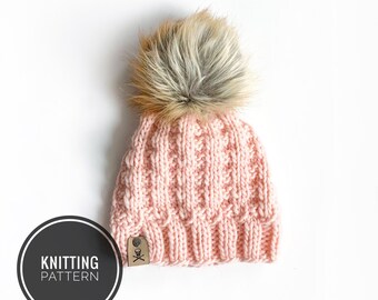 May include: A pink knitted beanie with a fluffy brown and white pom pom on top. The beanie has a small brown leather tag with a white X on it. The text "KNITTING PATTERN" is written in a circle on the left side of the image.