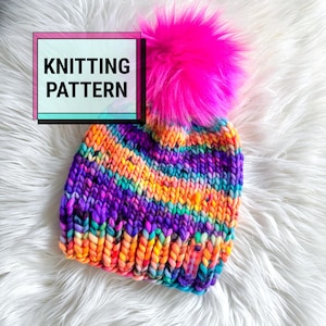 May include: A chunky knit beanie featuring a vibrant multicolored yarn in shades of orange, purple, blue, and yellow, topped with a large, bright neon pink faux fur pom-pom. A rectangular graphic overlay on the left side displays the text KNITTING PATTERN.